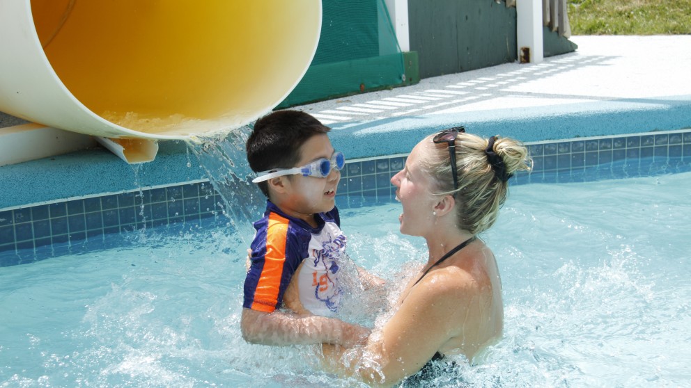 A Swimming Instructor helps a camper overcome his fear of the waterslide.